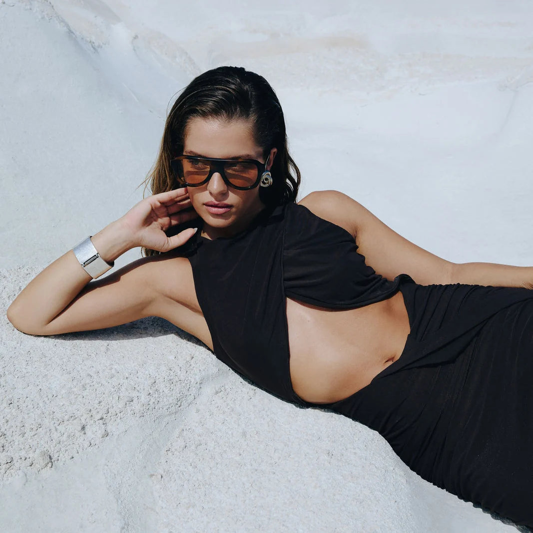 Μοντέλο φορά τα OS Sunglasses Formentera Giallo ξαπλωμένο σε λευκό βράχο