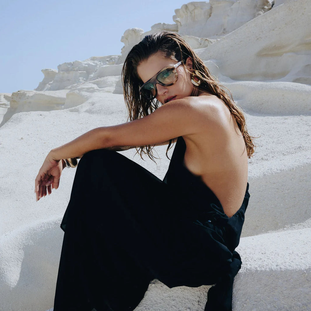 Μοντέλο με OS Sunglasses Formentera Verde καθισμένο σε λευκούς βράχους